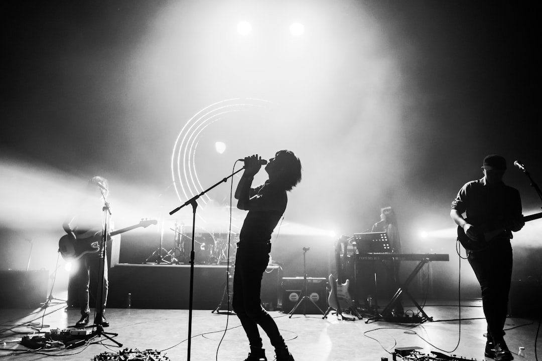 Rock vocalist performing live on stage at a packed concert venue